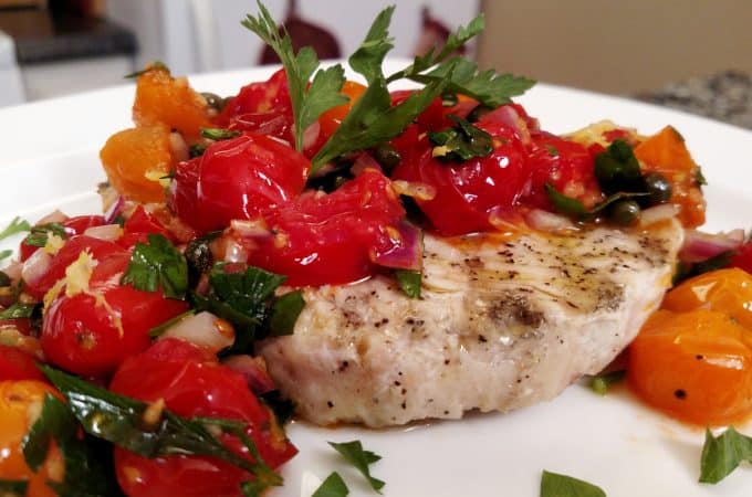 grilled swordfish with tomatoes and capers on a plate