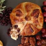 baked brie with grapes, crackers, rosemary on black table