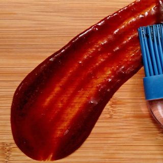 Homemade BBQ Sauce smeared on bamboo cutting board with brush