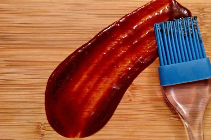 Homemade BBQ Sauce smeared on bamboo cutting board with brush