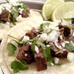 Street Tacos on corn tortilla with chopped onion, cilantro and lime wedges