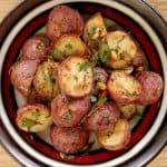 Roasted potatoes on a multicolored plate on bamboo cutting board