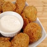 Fried Pickles ramekin of ranch dressing on white plate on bamboo cutting board