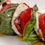 Caprese Salad, mozzarella, tomatoes, basil with a Balsamic Glaze and olive oil on white plate