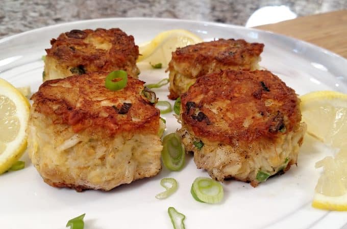 food network award winning crab cakes on a white plate with green onion garnish