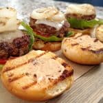 Hamburger Sliders on a wood cutting board, grilled onions, cheese