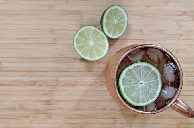 Overhead view of a Moscow Mule in a copper mug with a cut lime on a bamboo cutting board