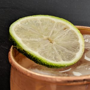 Closeup of Moscow Mule in Copper Mug with slice of lime and black background