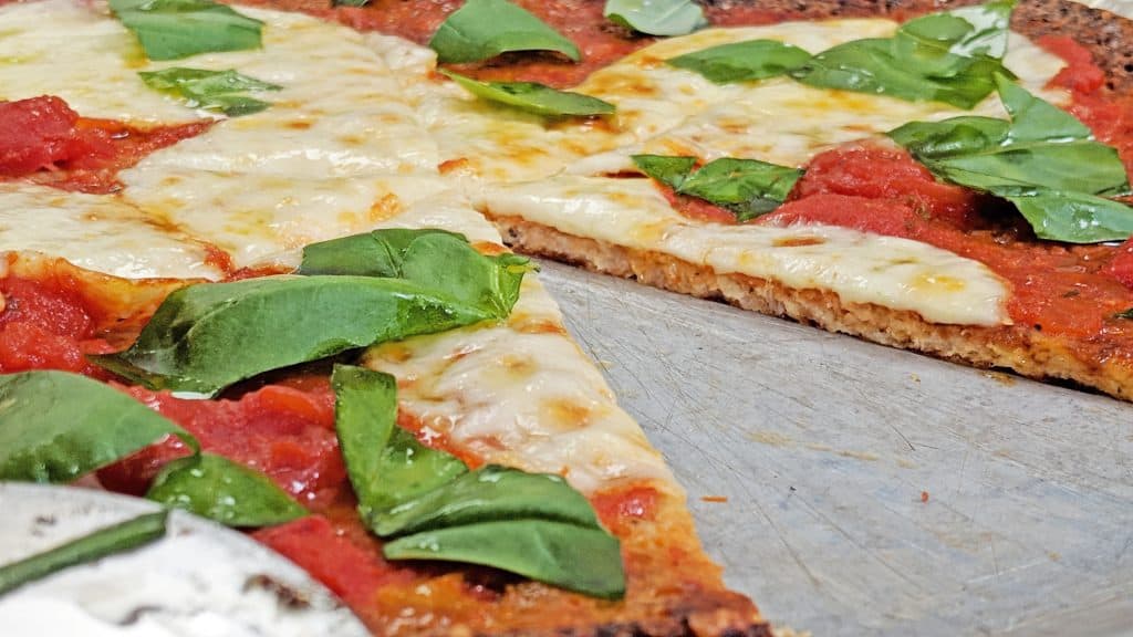 Keto Pizza with a Gluten Free Cauliflower Crust. pizza with slice missing.