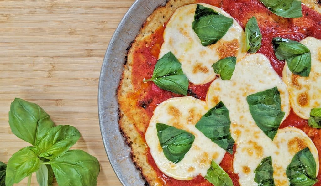 Keto Pizza with a Gluten Free Cauliflower Crust with fresh basil on brown cutting board. margherita pizza, Neapolitan pizza